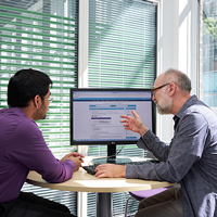 Two individuals talking in front of a computer