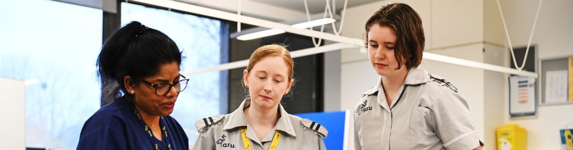 A nurse working with two Anglia Ruskin University student nurses in a hospital